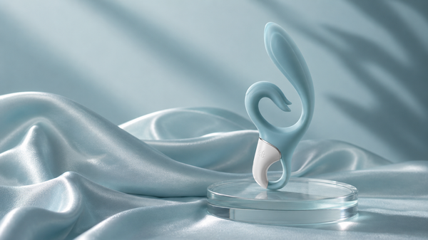 Vibromasseur rabbit posé sur un socle de verre, fond de satin bleu givré